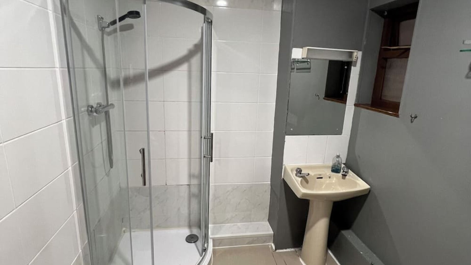 Bathroom with glass-enclosed shower, pedestal sink, and modern tiled design at Stay Inn Express.