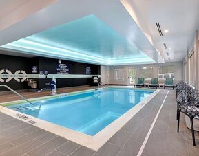 Indoor heated swimming pool with accessible lift, lounge chairs, and natural light at Tru By Hilton Lithia Springs.