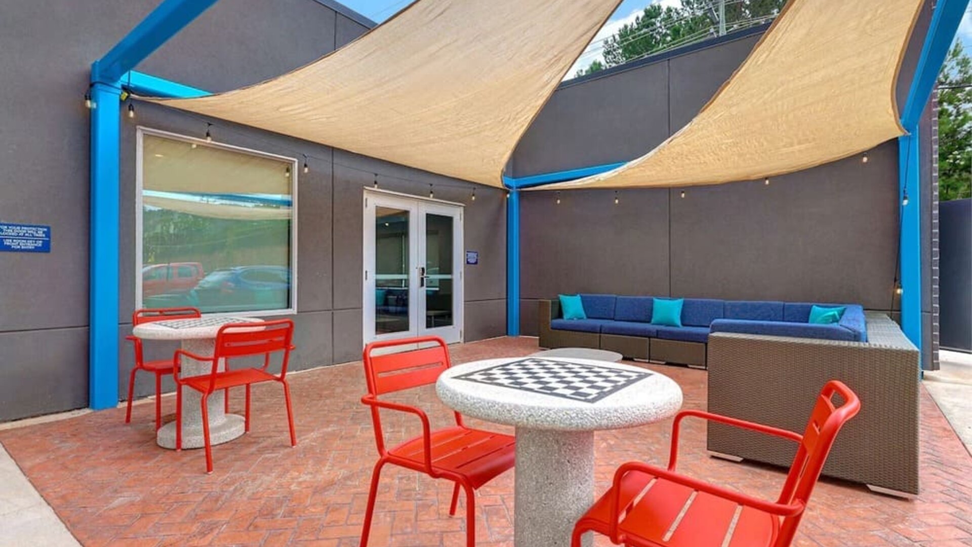 Outdoor patio with lounge seating, café tables, and shade sails at Tru By Hilton Lithia Springs.Modern reception area with front desk services and guest check-in at Tru By Hilton Lithia Springs.