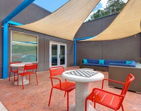 Outdoor patio with lounge seating, café tables, and shade sails at Tru By Hilton Lithia Springs.Modern reception area with front desk services and guest check-in at Tru By Hilton Lithia Springs.
