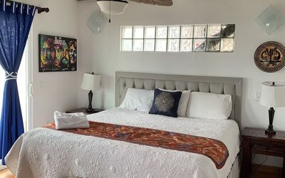 Bright king bedroom with elegant furnishings, exposed wooden beams, and adjoining lounge area at Casa Playa Baja Resort.