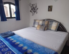 Cozy guest bedroom with queen-size bed, natural light, and charming coastal décor at Casa Playa Baja Resort.