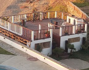 Elevated oceanfront deck with outdoor seating and fire pit overlooking the beach at Casa Playa Baja Resort.