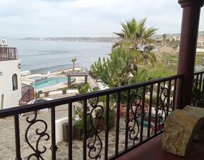 Private balcony overlooking the ocean, pool, and landscaped resort grounds at Casa Playa Baja Resort.