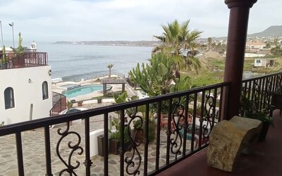 Private balcony overlooking the ocean, pool, and landscaped resort grounds at Casa Playa Baja Resort.