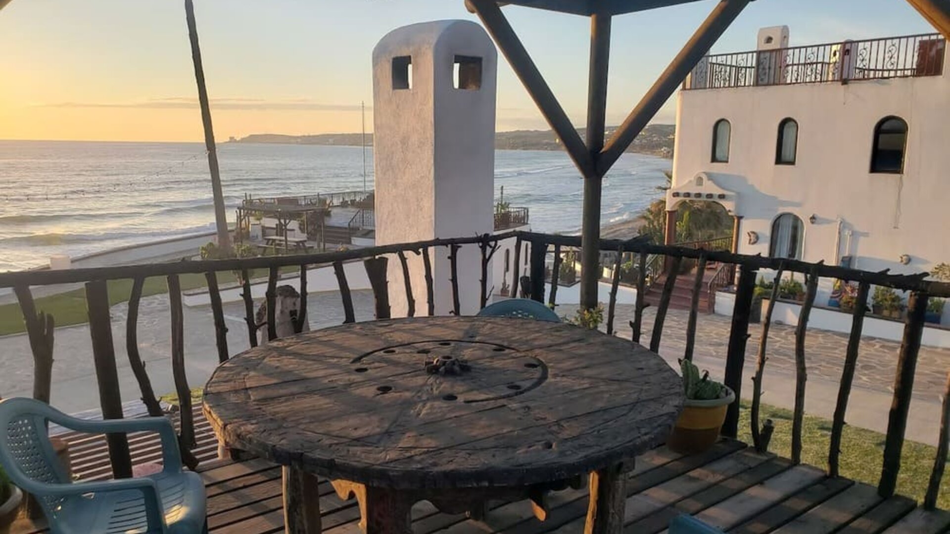 Oceanfront balcony with rustic seating area and panoramic sunset views at Casa Playa Baja Resort.