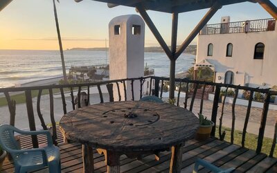 Oceanfront balcony with rustic seating area and panoramic sunset views at Casa Playa Baja Resort.