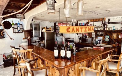 Rustic cantina-style bar with wooden seating, wine display, and beverage service at Casa Playa Baja Resort.