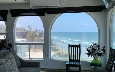Living area with ocean-view windows, seating, and coastal-inspired interiors at Casa Playa Baja Resort.