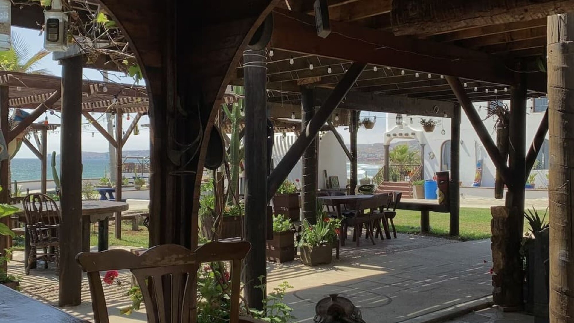 Open-air covered patio with rustic wooden seating and garden views at Casa Playa Baja Resort.