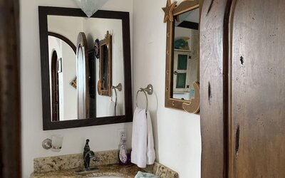 Bathroom vanity with granite countertop, sink, mirror, and rustic wood finishes at Casa Playa Baja Resort.