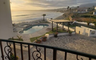 Balcony view of the resort grounds, swimming pool, and scenic coastline at Casa Playa Baja Resort.