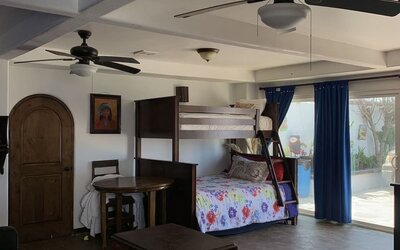 Family suite with bunk beds, lounge area, and direct access to the outdoor patio at Casa Playa Baja Resort.