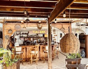 Rustic open-air tiki bar with handcrafted wood finishes, seating, and tropical atmosphere at Casa Playa Baja Resort.
