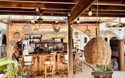 Rustic open-air tiki bar with handcrafted wood finishes, seating, and tropical atmosphere at Casa Playa Baja Resort.