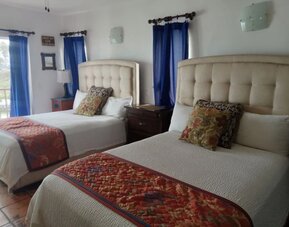 Double queen guest room with balcony access, natural light, and spacious accommodations at Casa Playa Baja Resort.