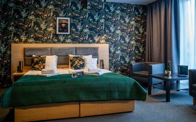 Spacious king guest room with botanical feature wall and seating area at Hotel Seven.