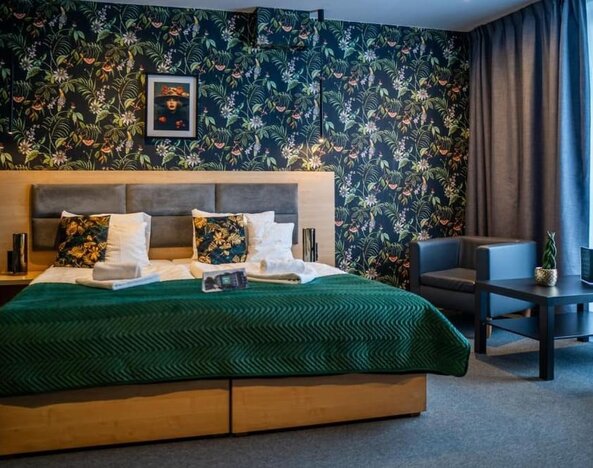 Spacious king guest room with botanical feature wall and seating area at Hotel Seven.