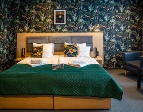 Stylish guest room with king-size bed, botanical feature wall and comfortable seating at Hotel Seven.