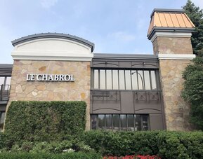 Exterior view of Le Chabrol Hotel Et Suites featuring its stone façade and main entrance.