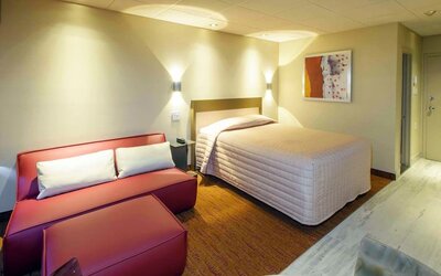 Cozy guest room with queen-size bed, lounge seating and warm contemporary décor at Le Chabrol Hotel Et Suites.