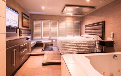 Spacious suite with king-size bed, in-room jacuzzi and seating area at Le Chabrol Hotel Et Suites.