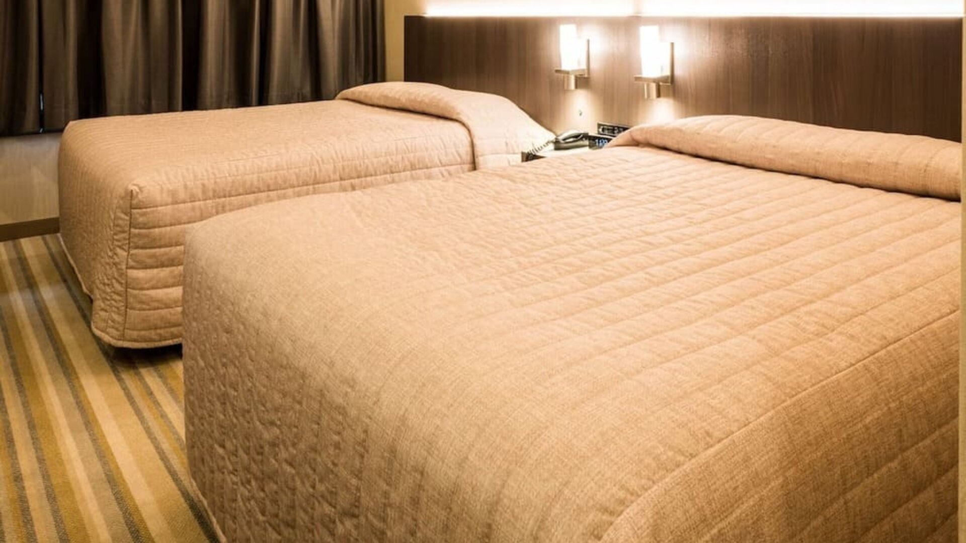 Twin guest room featuring two double beds, contemporary furnishings and warm lighting at Le Chabrol Hotel Et Suites.