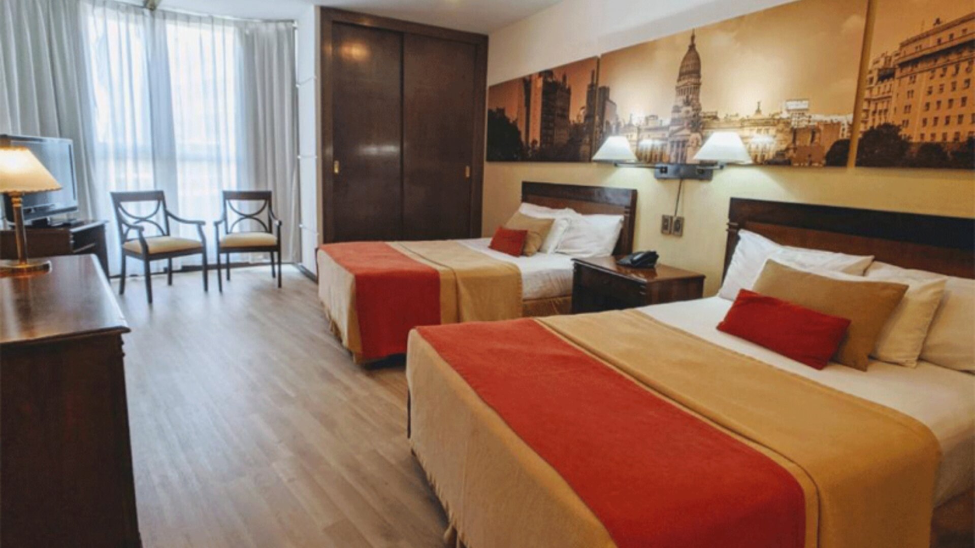 Spacious guest room at HR Plaza Luxor featuring two double beds, hardwood furnishings, city-themed artwork, and ample natural light from large windows.