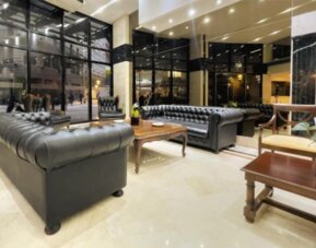 Lounge section within the lobby featuring classic leather sofas, large floor-to-ceiling windows, and a relaxing space for socializing or unwinding at HR Plaza Luxor.