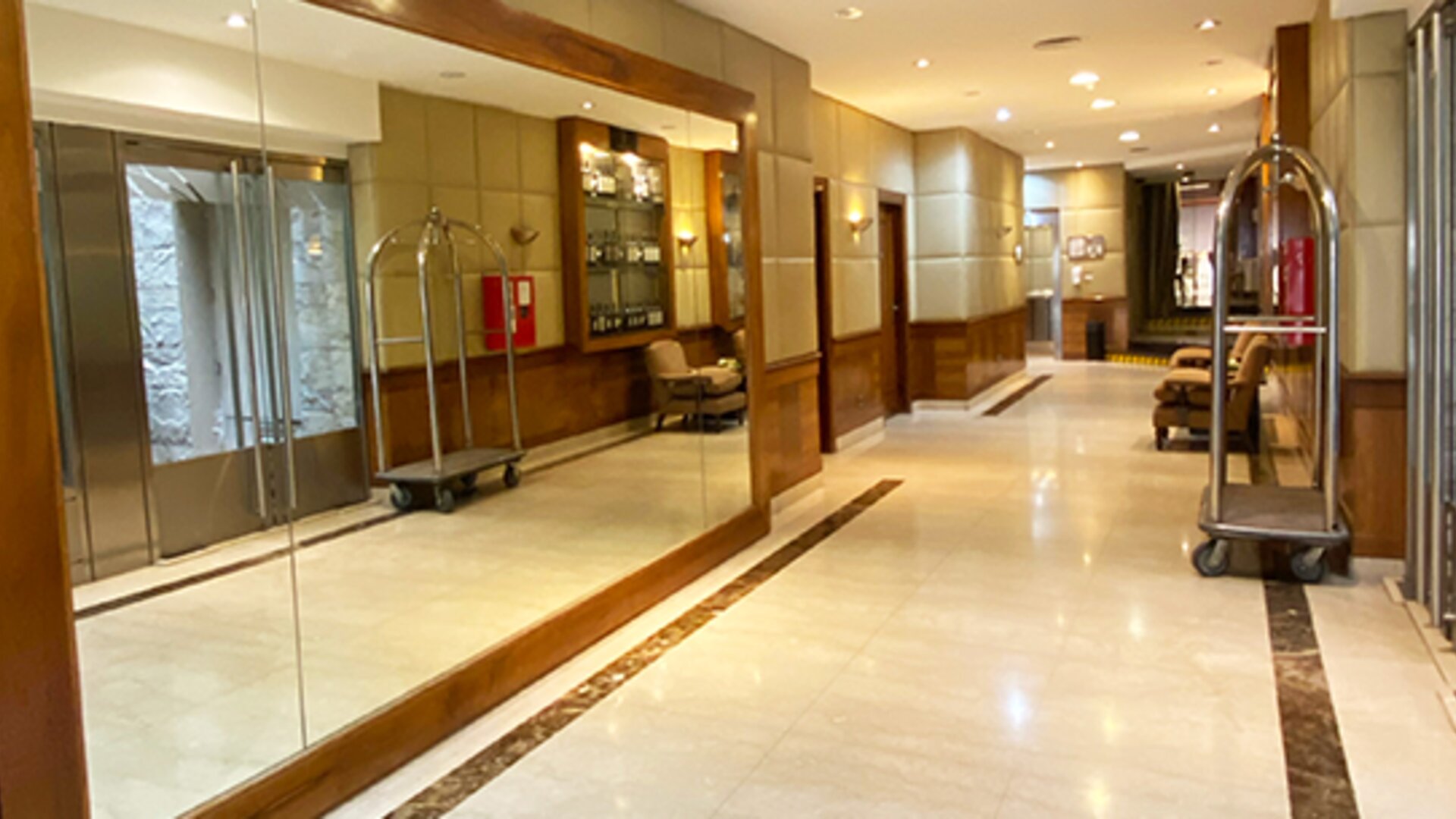 Elegant lobby corridor with marble flooring, mirrored walls, comfortable seating areas, and luggage carts providing a welcoming arrival experience at Hotel Lafayette.