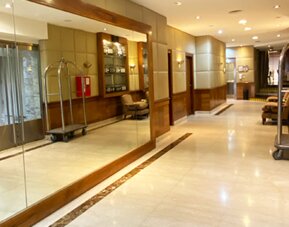 Elegant lobby corridor with marble flooring, mirrored walls, comfortable seating areas, and luggage carts providing a welcoming arrival experience at Hotel Lafayette.