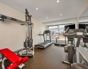 Modern fitness centre with cardio machines and strength training equipment at Hotel Brossard.