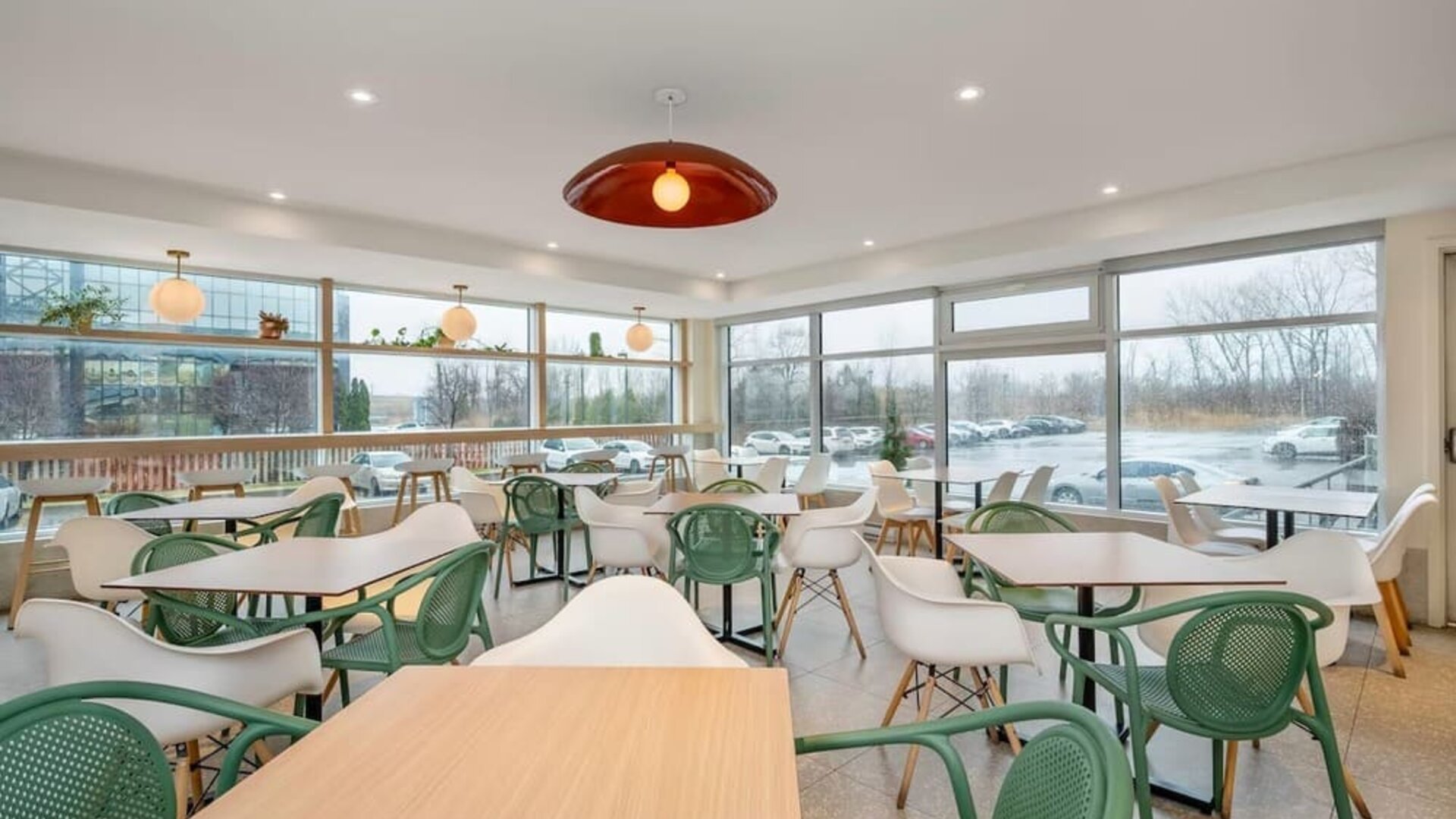 Bright dining area with floor-to-ceiling windows and contemporary seating at Hotel Brossard.