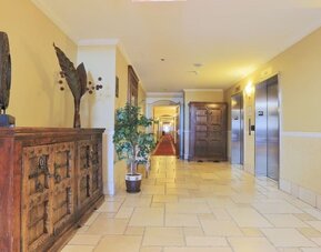 Bright hotel corridor with elevator access and elegant décor at Hotel Brossard.