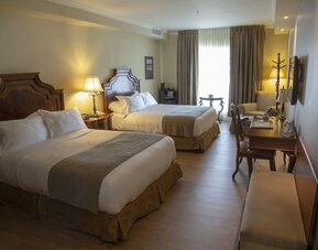 ontemporary guest room featuring two queen beds, workspace and modern amenities at Hotel Brossard.