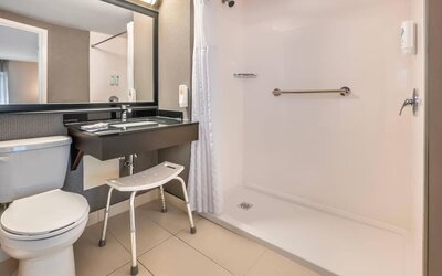 Accessible guest bathroom featuring a roll-in shower, grab bars and convenient accessibility features at Comfort Inn Laval.