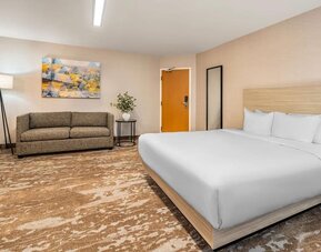 Spacious king guest room with sofa seating and contemporary décor at Comfort Inn Laval.
