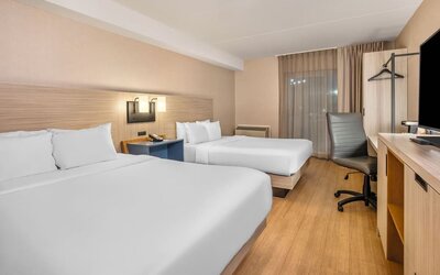 Spacious guest room with two queen beds, work desk and modern furnishings at Comfort Inn Laval.