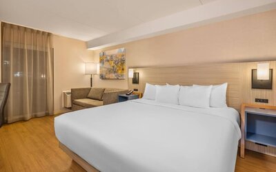 Comfortable king guest room with sofa seating and modern amenities at Comfort Inn Laval.