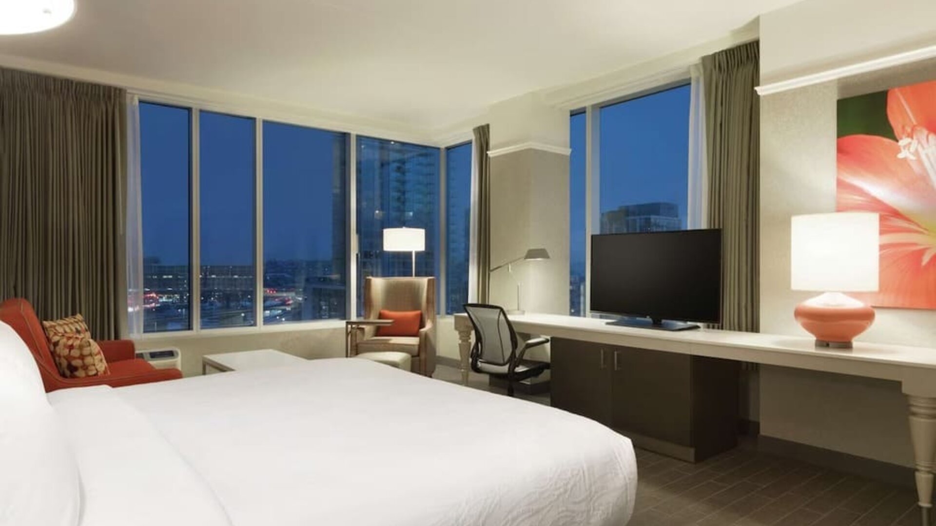 Spacious king guest room with floor-to-ceiling windows, city views, workspace and comfortable seating at Hilton Garden Inn Calgary Downtown.