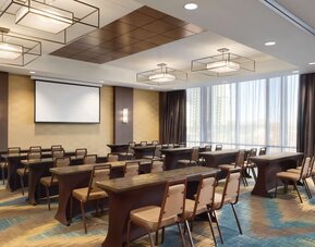 Modern meeting room with classroom-style seating and presentation screen at Hilton Garden Inn Calgary Downtown.