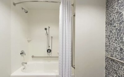 Accessible guest bathroom with grab bars, bathtub and shower combination at Hilton Garden Inn Calgary Downtown.
