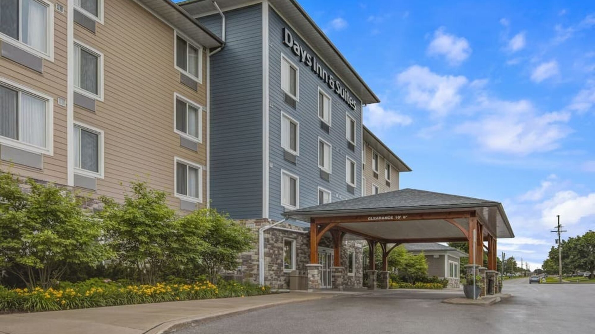 Exterior view of Days Inn & Suites By Wyndham Lindsay with landscaped entrance and covered driveway.