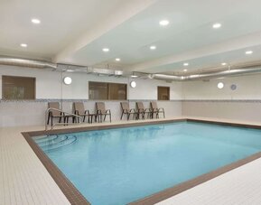 Spacious indoor swimming pool with easy-entry steps and poolside seating at Days Inn & Suites By Wyndham Lindsay.