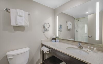 Modern guest bathroom with illuminated vanity, walk-in shower and complimentary toiletries at Days Inn & Suites By Wyndham Lindsay.