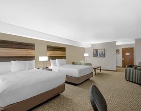 Spacious guest room with two queen beds, comfortable seating area and modern amenities at Days Inn & Suites By Wyndham Lindsay.