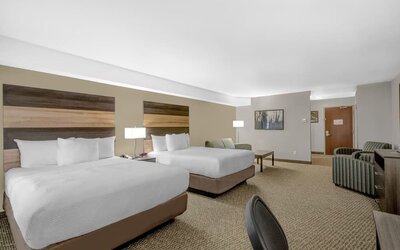 Spacious guest room with two queen beds, comfortable seating area and modern amenities at Days Inn & Suites By Wyndham Lindsay.