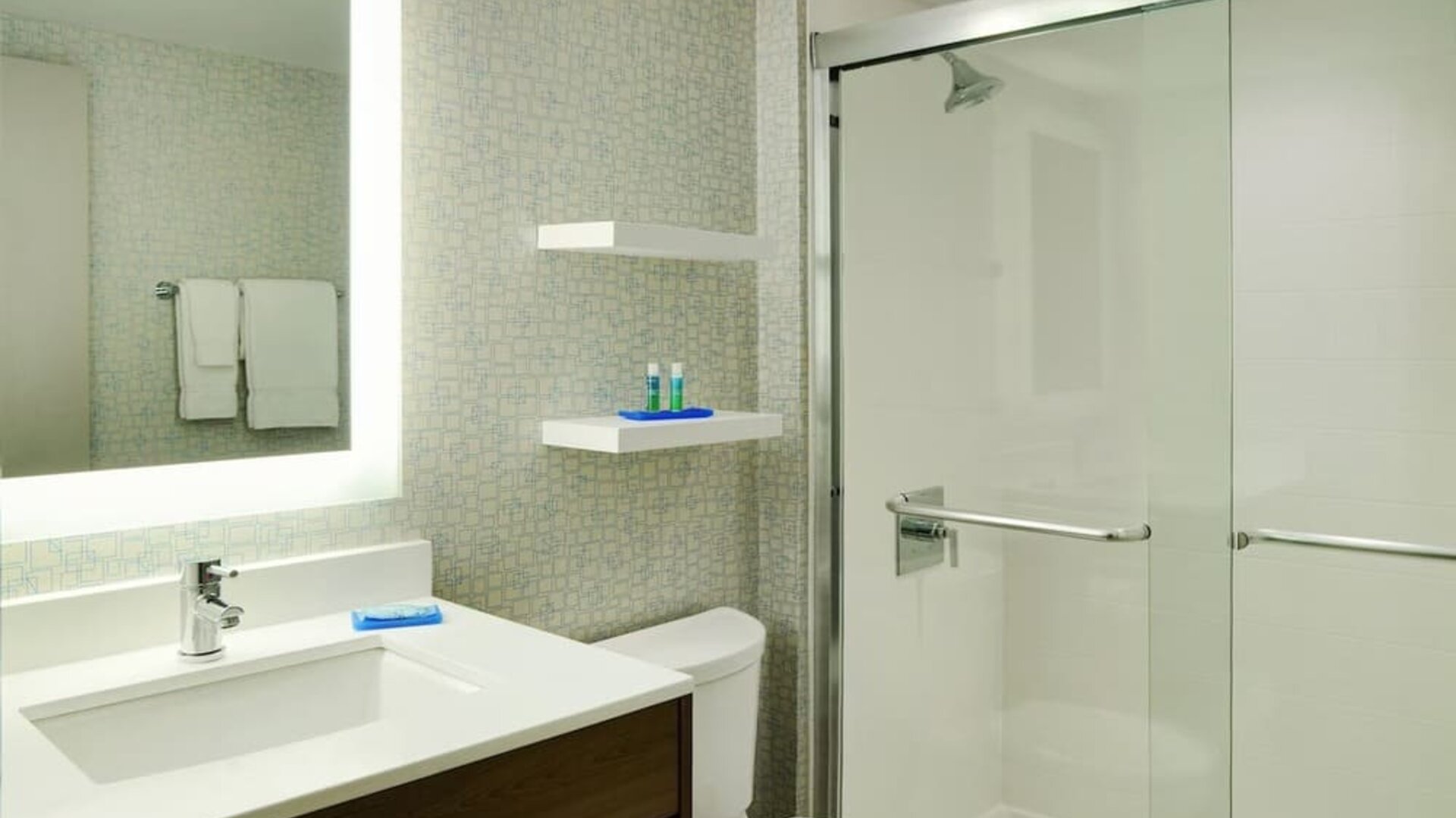 Contemporary bathroom with glass-enclosed shower, illuminated mirror and sleek vanity at Holiday Inn Express Toronto Downtown.