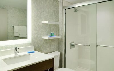 Contemporary bathroom with glass-enclosed shower, illuminated mirror and sleek vanity at Holiday Inn Express Toronto Downtown.