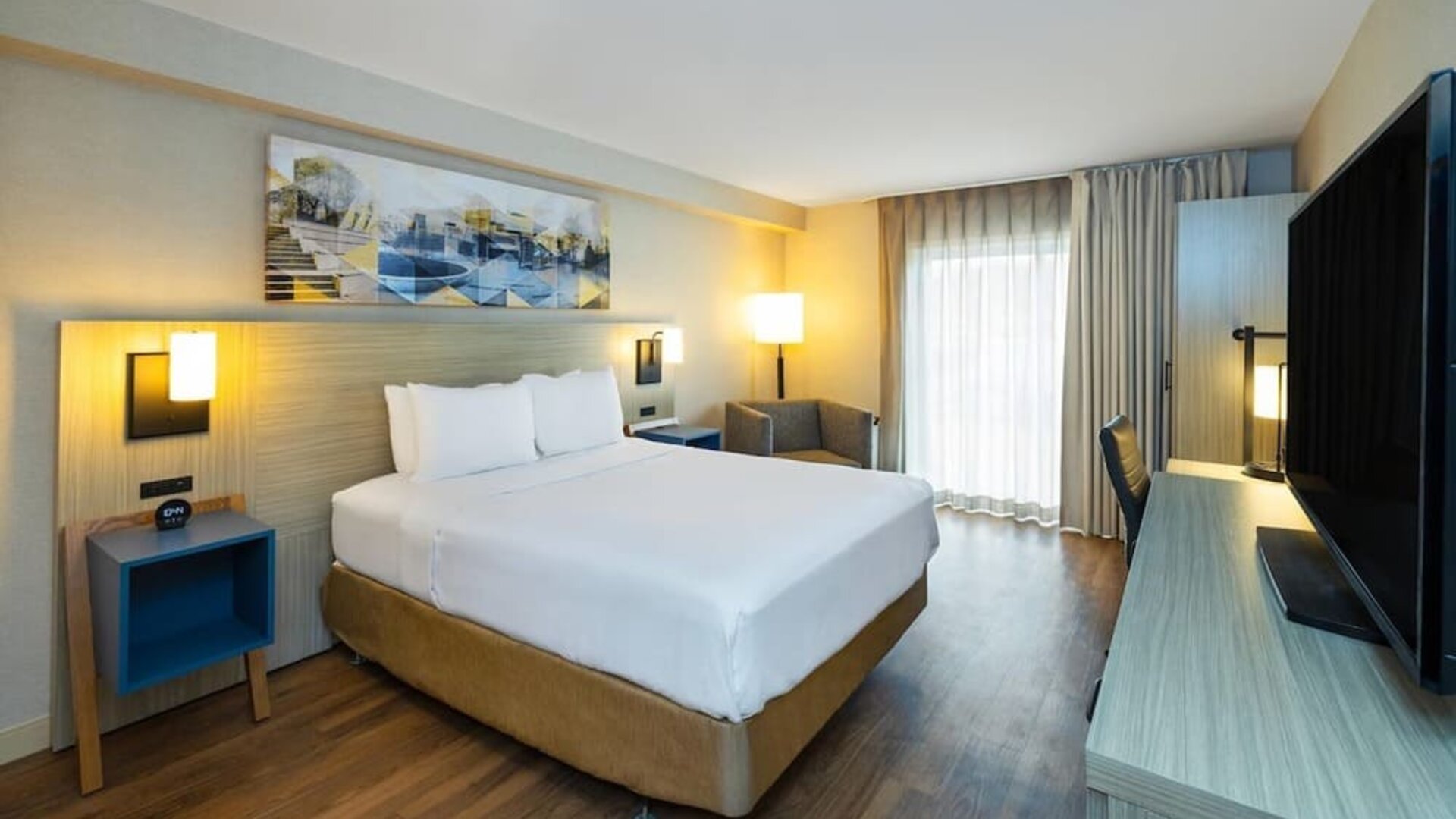 Bright king guest room with workspace, flat-screen TV, and cozy seating area at Comfort Inn Sydney.